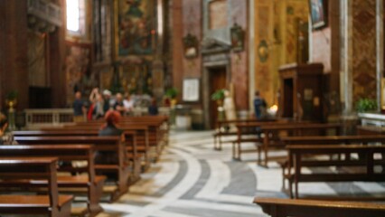 Interior of a church with defocused people in background, featuring blurred pews and religious decor in an atmospheric setting, emphasizing a serene, contemplative mood.