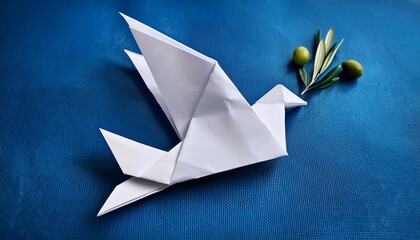 paper origami dove of peace with olive department on a blue background