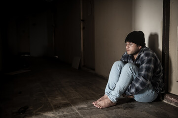 A drug addict is paranoid after taking drugs, sitting in the hallway of an abandoned building.