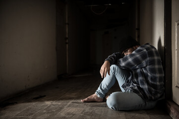 A drug addict is paranoid after taking drugs, sitting in the hallway of an abandoned building.