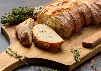 Sliced ​​baguette with flax and spices on a wooden cutting board