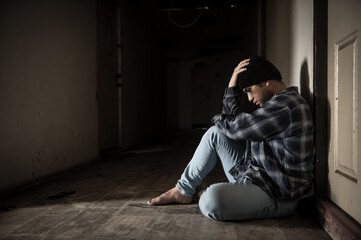 A drug addict is paranoid after taking drugs, sitting in the hallway of an abandoned building.