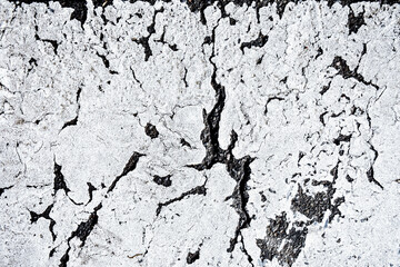 The texture of a cracked white surface with black cracks. The image shows a rough texture that creates contrast between light and dark areas.