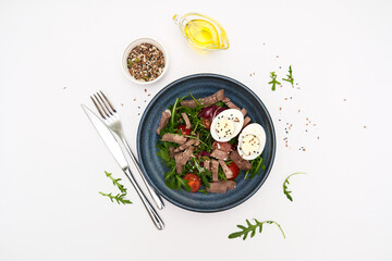 A fresh salad with tender beef, nutritious eggs, and fresh greens aragula, olive oil, seeds perfect for healthy meals anytime.