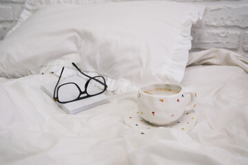 A warm and inviting composition that beautifully features a mug, various glasses, and soft white bedding