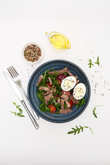 A fresh salad with tender beef, nutritious eggs, and fresh greens aragula, olive oil, seeds perfect for healthy meals anytime.