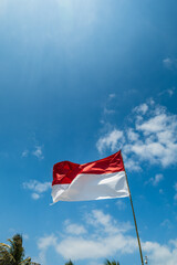 Indonesia flag waving in wind on blue sky background. International relations and tourism concept. 
