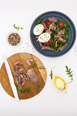 A fresh salad with tender beef, nutritious eggs, and fresh greens aragula, olive oil, seeds perfect for healthy meals anytime. Cutting ingredients on cutboard.
