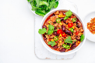 Chili con carne with minced beef, beans, paprika, corn, cilantro, jalapeno pepper in tomato sauce, white background, top view