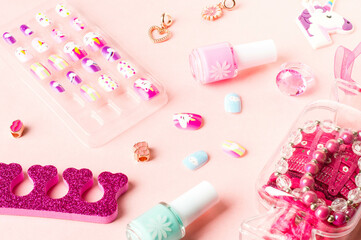 Pink accessories. Colored false nails, nail polish bottles, a separator for pedicures, and jewelry items for girls.