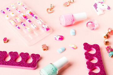 Pink accessories. Colored false nails, nail polish bottles, a separator for pedicures, and jewelry items for girls.