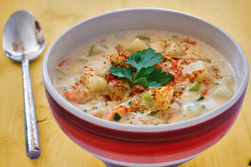 bowl of New England clam chowder topped with fresh parsley, with a spoon on the side