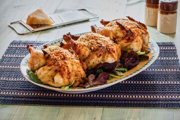 platter of oven roasted cornish hens on a bed of mixed greens