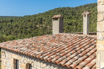 A horizontal texture of part of an old brown roof of clay tiles with chimneys