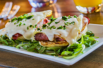 ham and cheese benedict on a bed of mixed greens