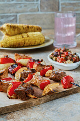 chicken and steak kebabs with bell pepper, tomato, and red onion, served with grilled corn on the cobb