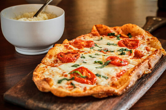 margherita pizza flatbread topped with mozzarella, blistered tomatoes, and fresh basil - Powered by Adobe