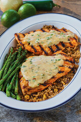 southwest style grilled chicken on a bed of wild rice with grilled asparagus on a white platter