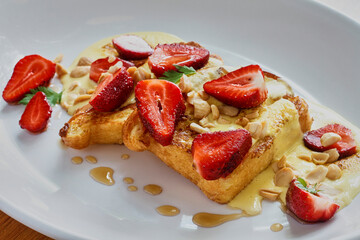 french toast topped with fresh strawberries and maple syrup