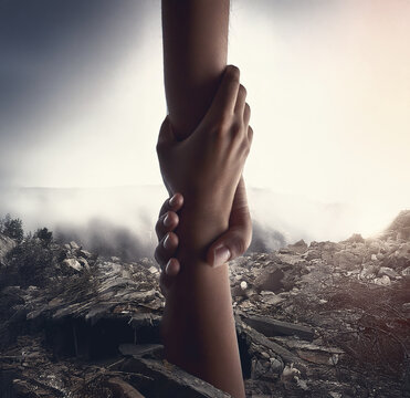 A helping hand extends from the ruins of a building destroyed by an earthquake