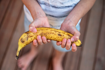 Hands of a child holding a ripe banana