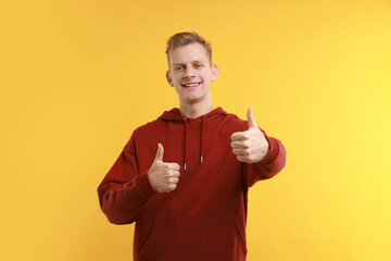 Happy man showing thumbs up on yellow background. Like gesture