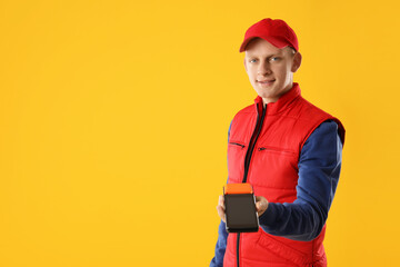 Happy courier with payment terminal on yellow background, space for text