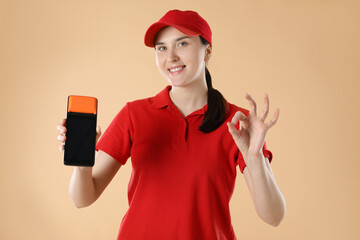 Happy courier with payment terminal showing OK gesture on beige background