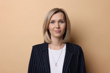 Portrait of businesswoman in jacket on beige background