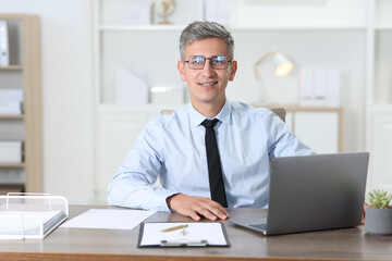 Fototapeta premium Portrait of businessman at table in office