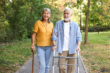 Senior couple with walking frame and cane in park