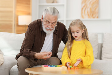 Fototapeta premium Grandpa and his granddaughter playing with math game Times table tray at home