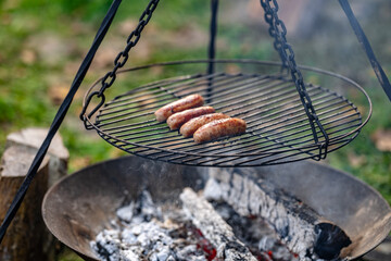 A grill with four hot dogs on it, cooking over a fire