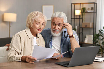 Fototapeta premium Pension savings. Senior couple planning budget at wooden table indoors