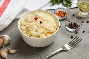 Bowl with delicious sauerkraut and different spices on grey background