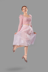 Naklejka premium Beautiful young woman jumping on grey background