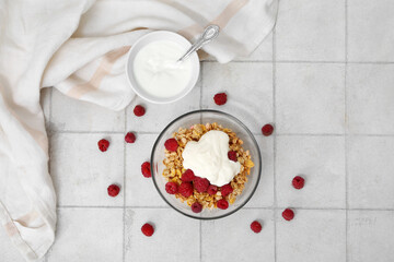 Bowls of tasty granola with yogurt on light tile background