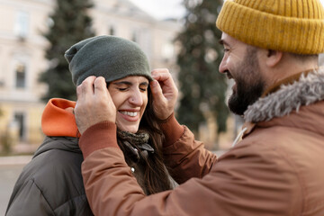 Man gently adjusting woman's beanie in playful winter scene