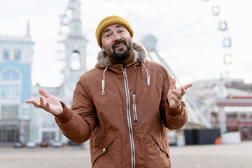 Bearded man gesturing surprise in amusement park during cold season
