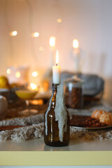 Books, e-reader, tea, orange juice, fruit, snacks, yarn, blanket and lit candles on the table. Autumn or winter hygge at home. Selective focus.