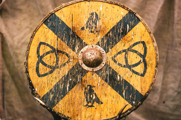 A battered and worn Viking shield with a cross on it