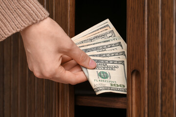 Woman hiding dollar banknotes in commode, closeup