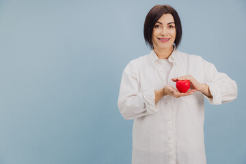 Middle aged woman holding red heart promoting cardiovascular health and disease prevention
