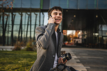 man hold thermos talk on mobile phone man and sit on bench outdoor