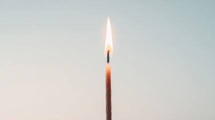 Single lit candle flame against a light background.