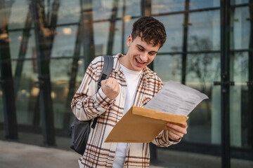 Young adult man student open and read files from envelope outdoor