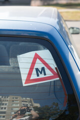 Fototapeta premium photo, symbol, driver, triangle, letter, automobile, learner, m, reflection, photography, image, blue, car, sign, displaying, vehicle, red, window