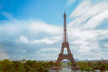 Stunning long exposure shot of the Eiffel Tower with soft, blurred clouds in a vibrant blue sky. Ideal for travel, landscape, or cultural projects showcasing Paris s iconic beauty.