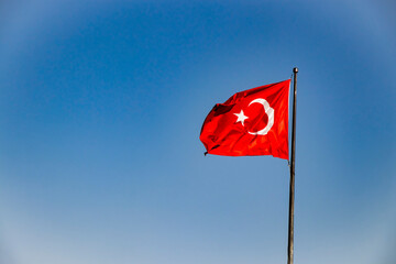 a waving, red, Turkish flag with blue sky in the background in the city of Göynük in Turkey