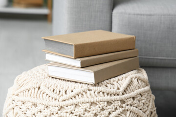 Stack of old books on pouf in living room, closeup